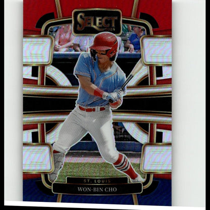 Red helmeted baseball player in a light blue jersey and white pants, captured mid-swing on a glossy trading card with gold trim.