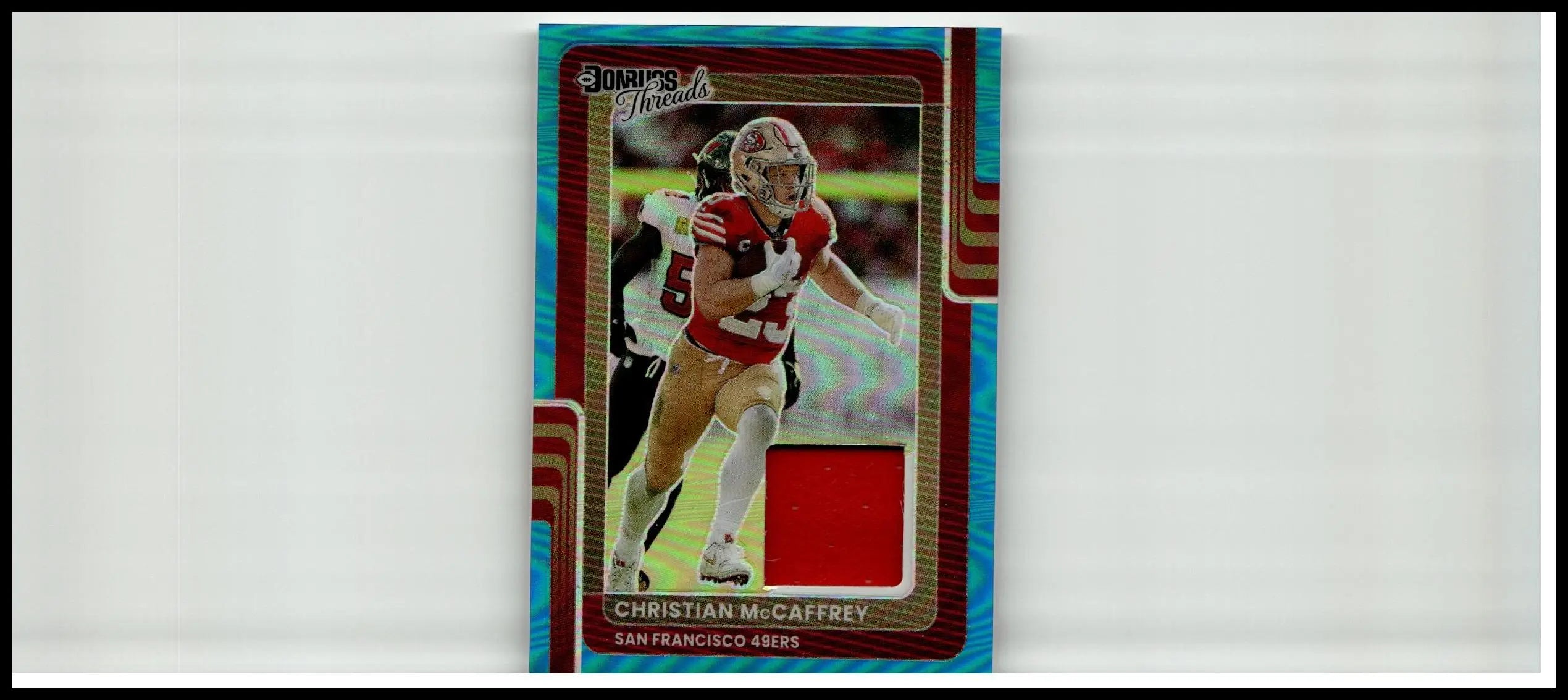 This is a red and gold christian mccaffrey donruss football trading card with holographic blue border from 2025 Donruss Optic