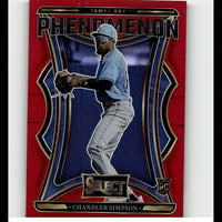 Red and blue tampa bay phenomenon baseball trading card featuring chandler simpson in a light blue jersey, gray pants, white cap with visor, black batting gloves, and gold-trimmed design elements.