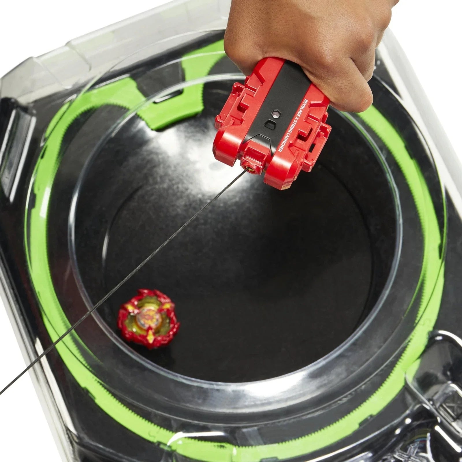 Red and black beyblade launcher with green accents being used to launch a red, yellow, and gold beyblade into the arena.