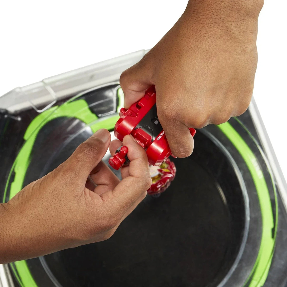Red and black beyblade launcher being held by a hand above its arena.