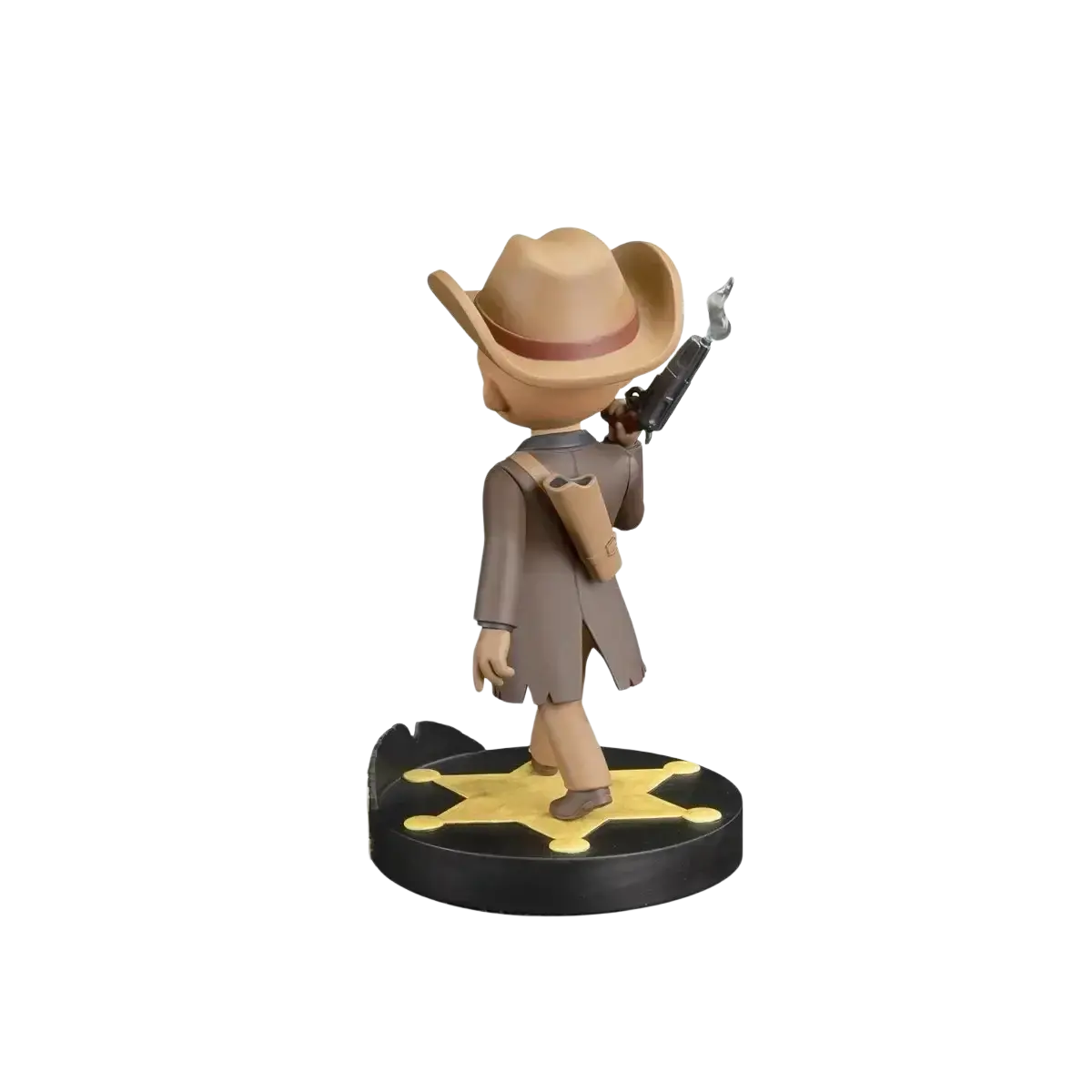 A tan cowboy figurine with a brown hat and coat, holding a smoking revolver, stands on a black circular base featuring a yellow star.