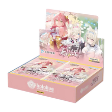 Pink cardboard display box for the hololive elite spark official card game, featuring anime-style artwork of three characters on its front and side panels.