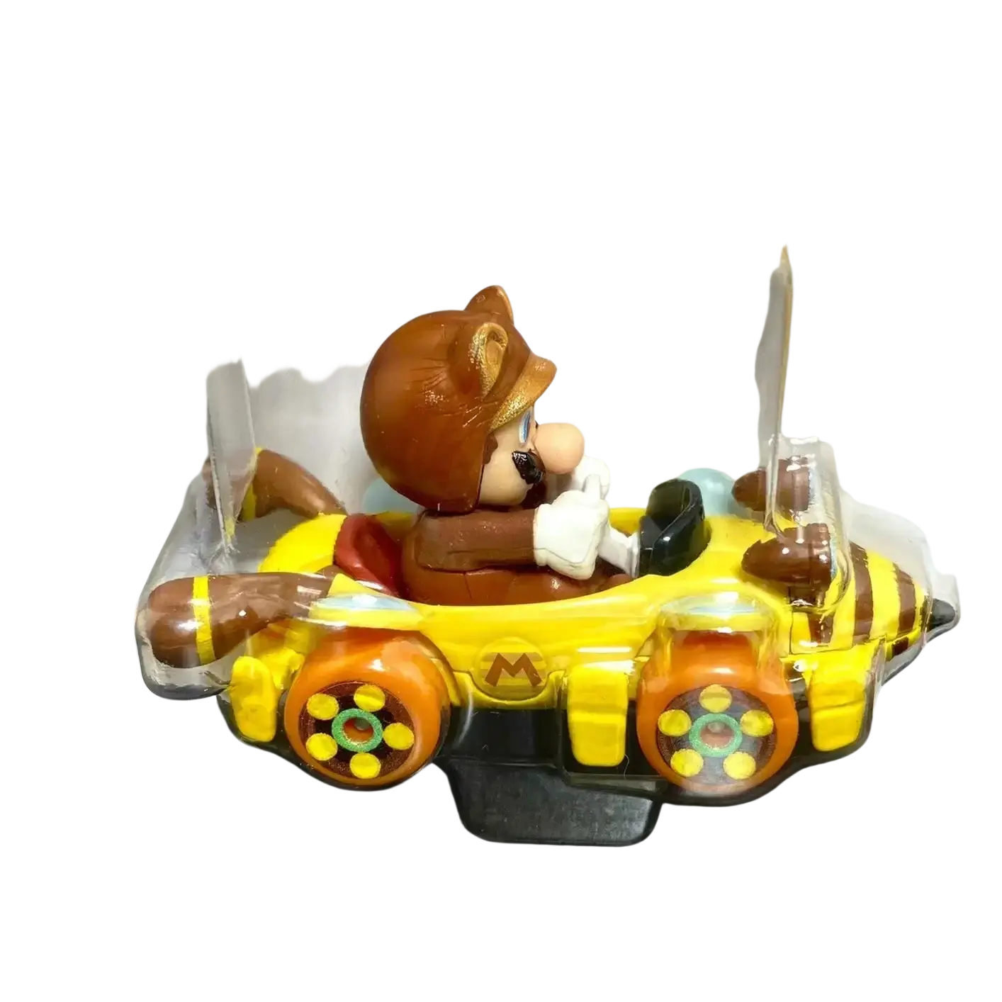 Yellow and brown teddy bear in a car toy with clear plastic packaging.
