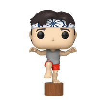 Karate Kid Daniel Crane Kick Funko Pop #2080 by Funko balancing on one leg on a wooden stump in his iconic pose.