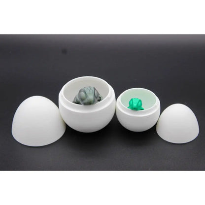 Two white egg-shaped containers with small frog figurines.