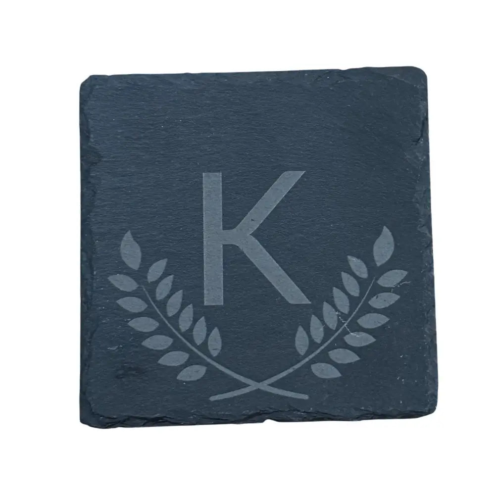 Engraved slate coaster with a laurel wreath design and the letter ’K.’