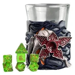 A translucent green polyhedral dice set with a red and black stranger things logo on the side of its glass holder.
